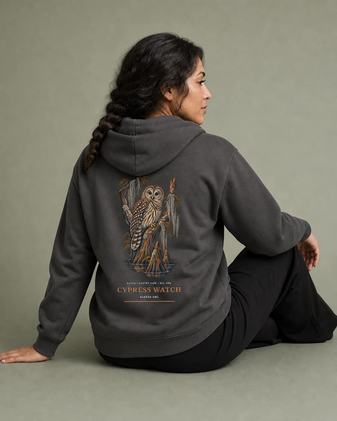 Adult wearing the Cypress Watch hoodie in Charcoal, back view
